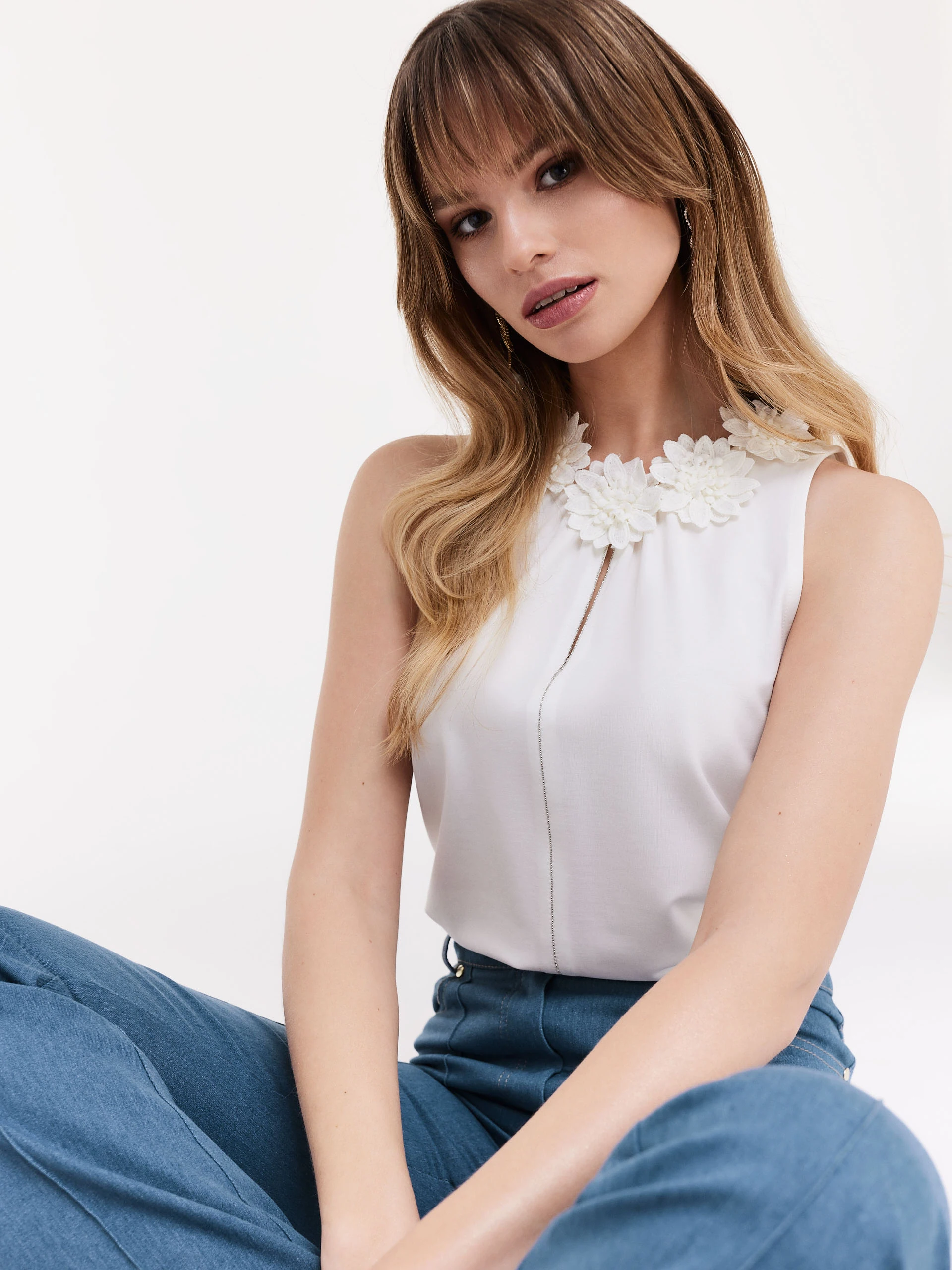 White sleeveless blouse with decorative patches