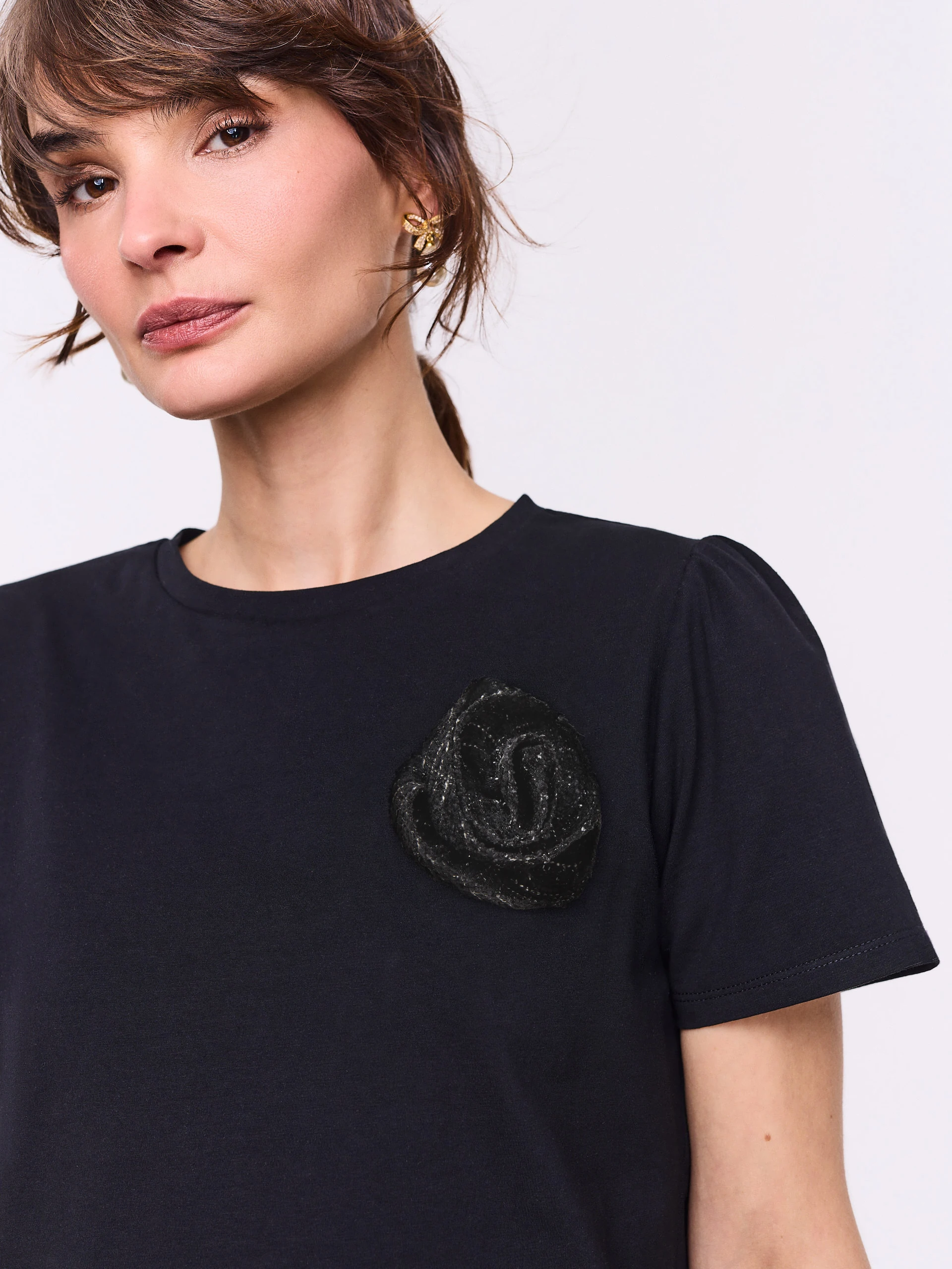 Black short-sleeved blouse with a flower-shaped brooch