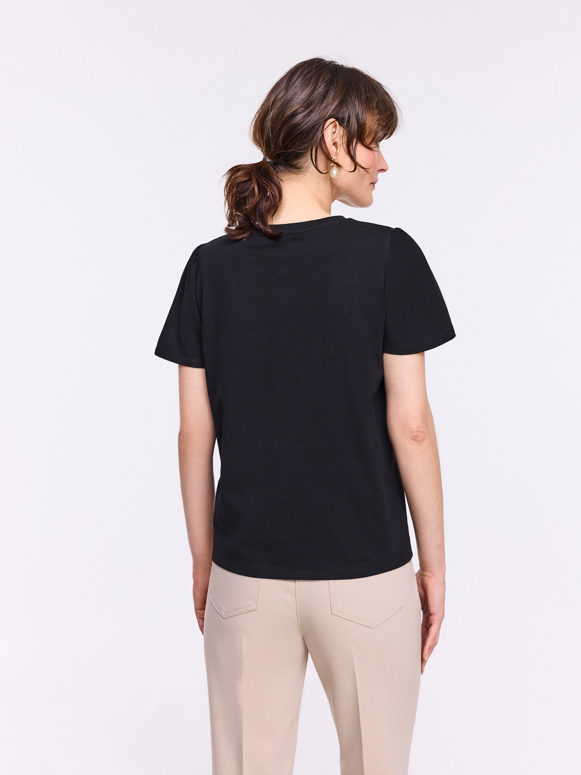 Black short-sleeved blouse with a flower-shaped brooch