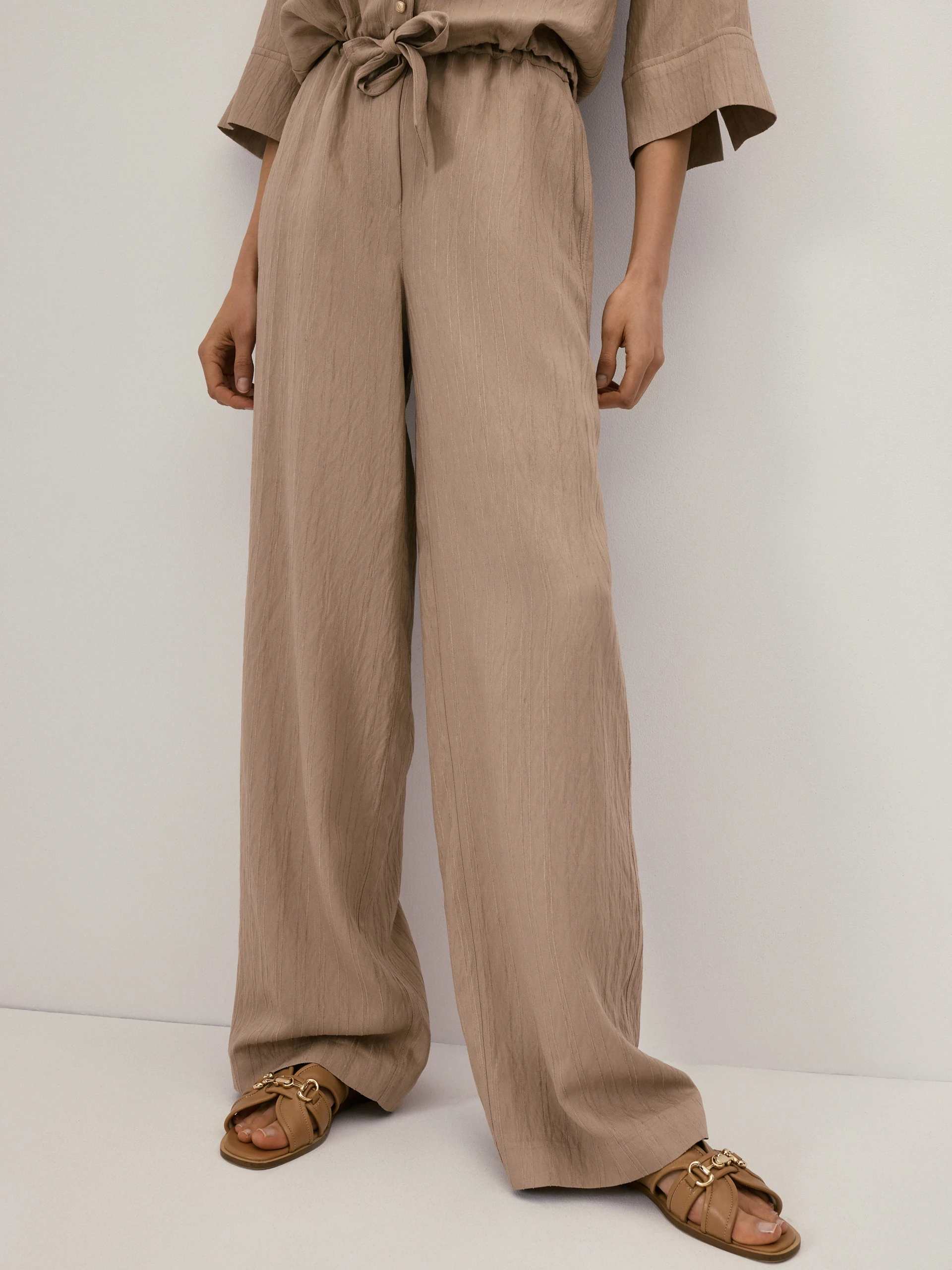 Beige high-waisted trousers with a subtle ribbed pattern