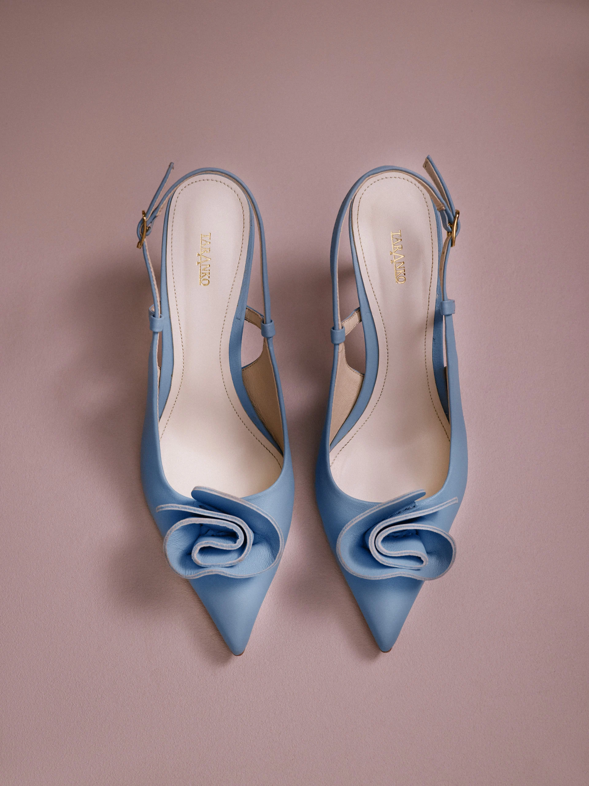 Light blue leather pumps with a flower detail and an open heel