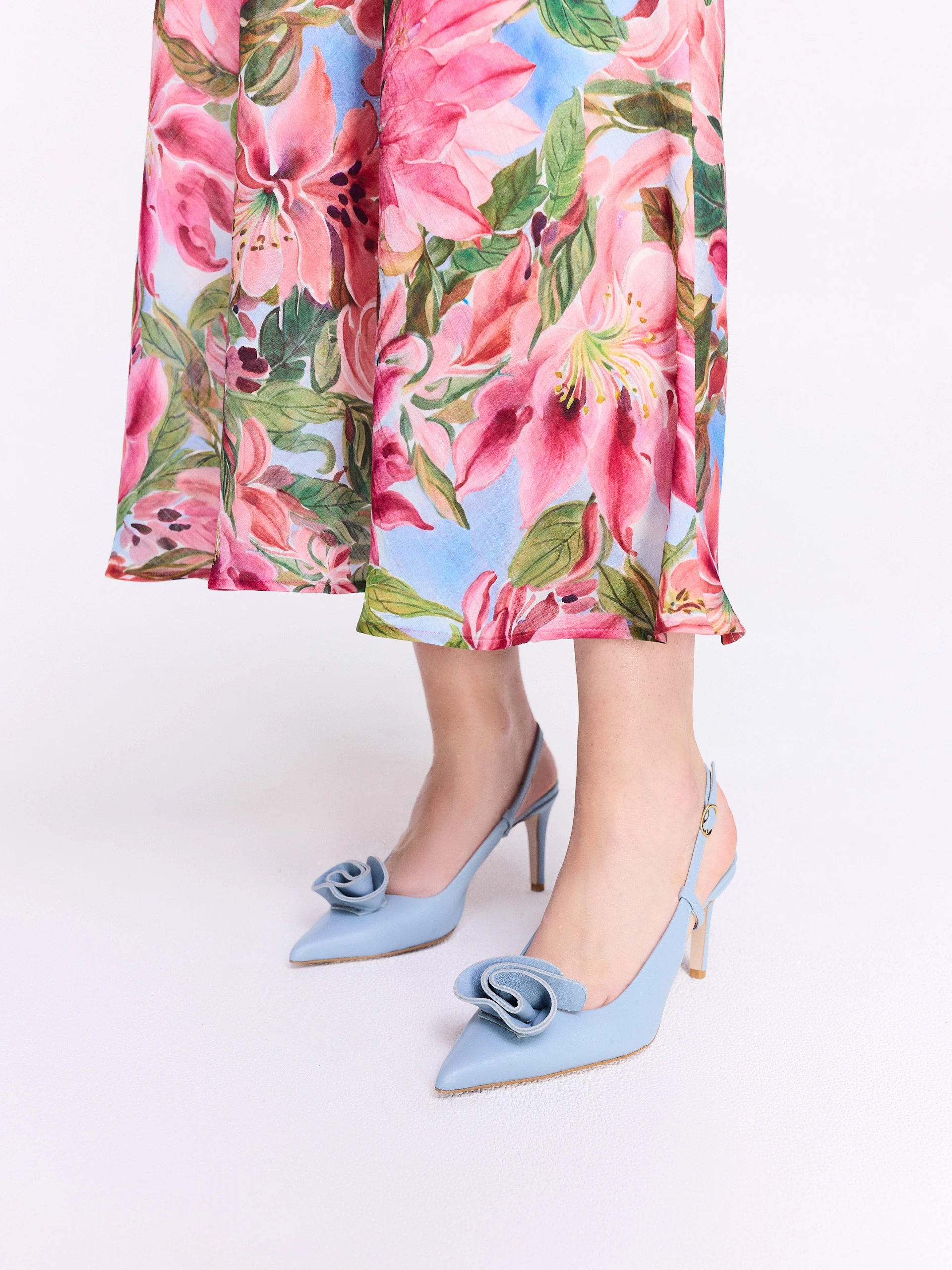 Light blue leather pumps with a flower detail and an open heel