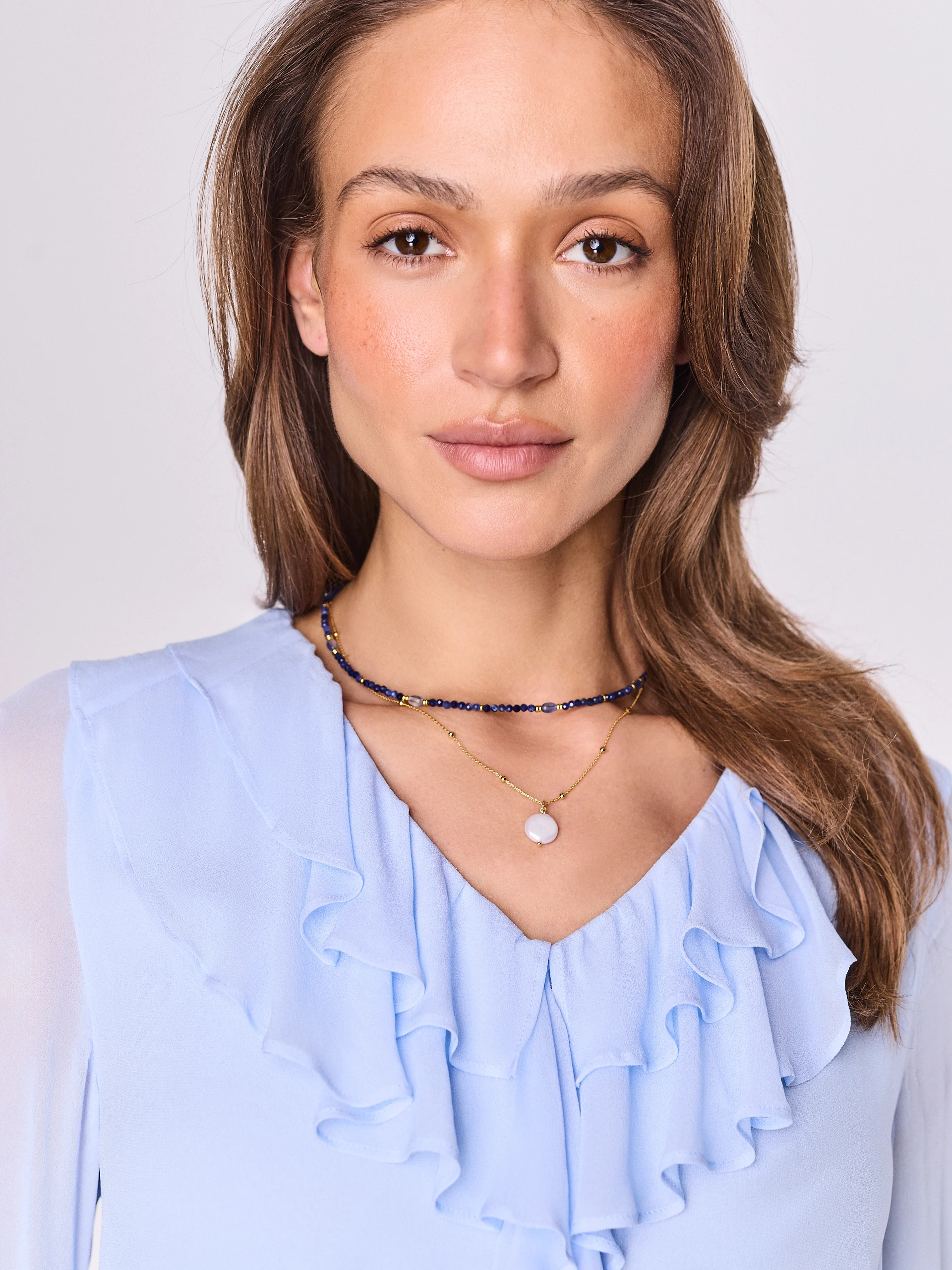 A set of two beaded necklaces with gold-colored pendants