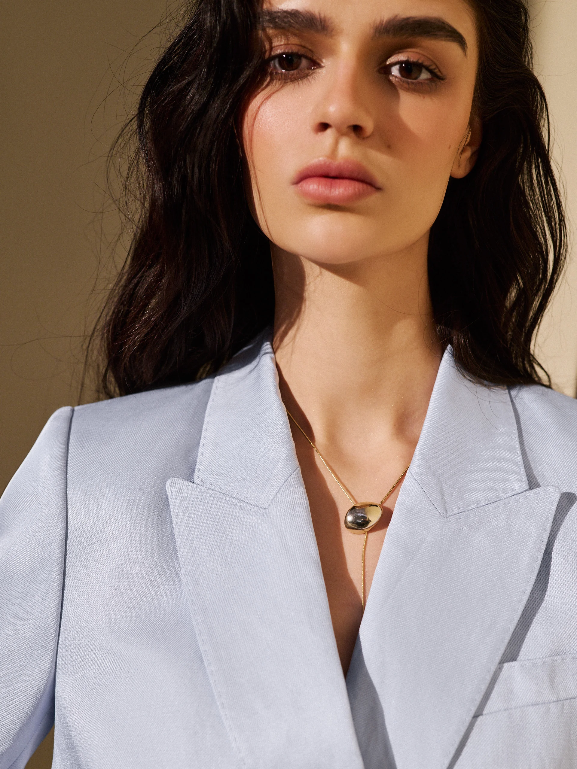 A gold-colored necklace with a pendant and a clasp