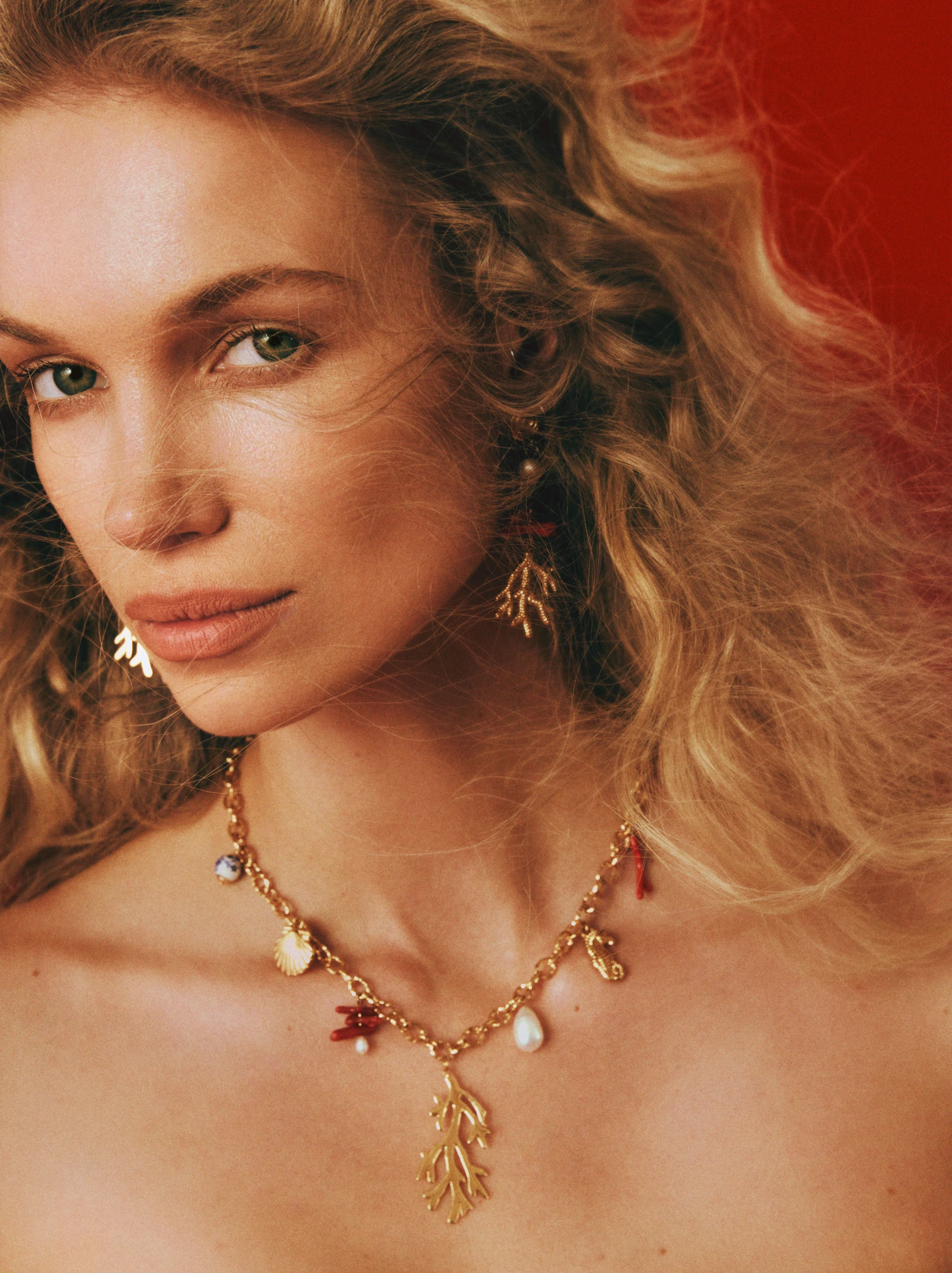 A gold-colored necklace with decorative pendants featuring a natural pearl