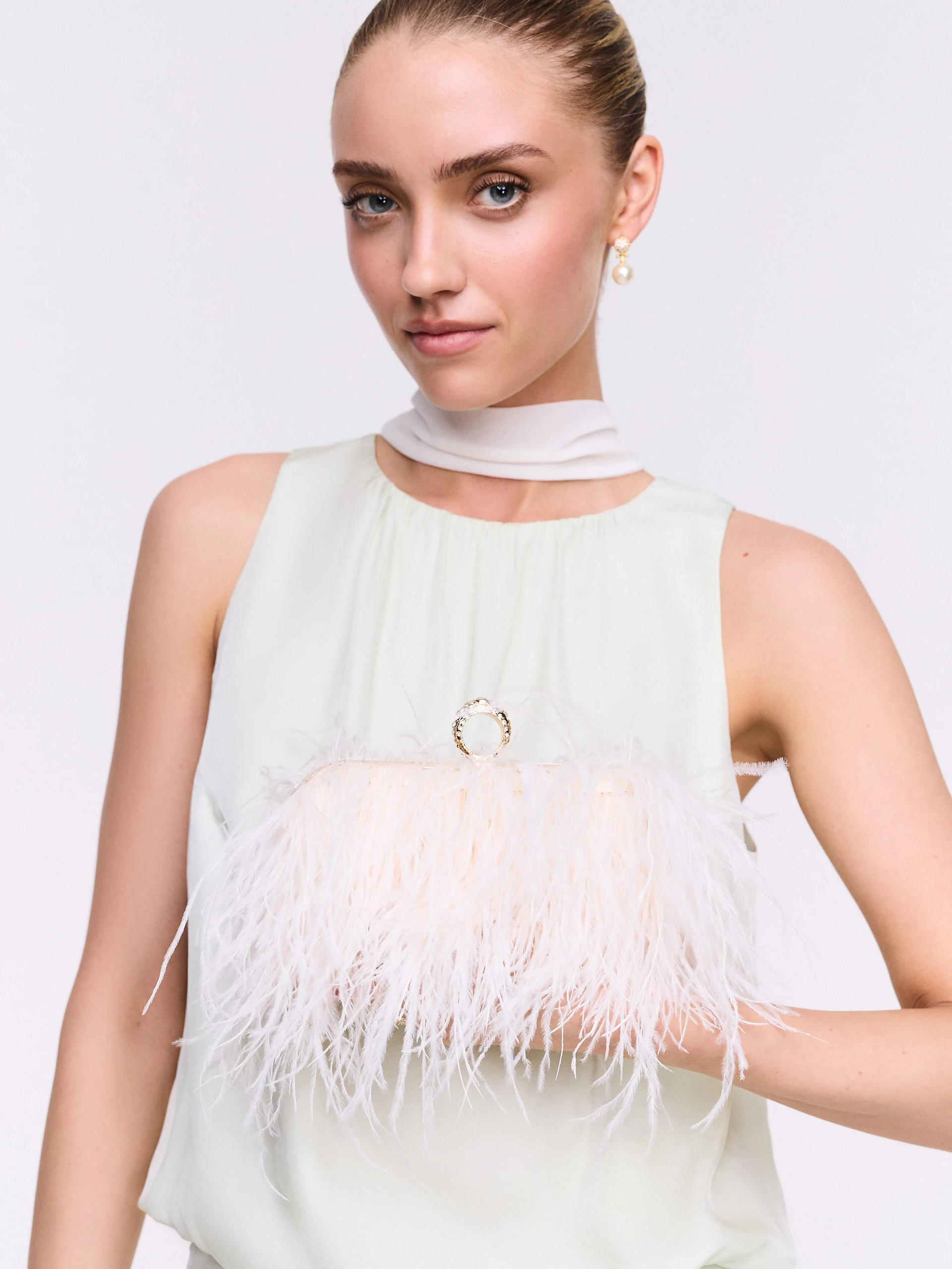 A small cream-colored handbag embroidered with feathers