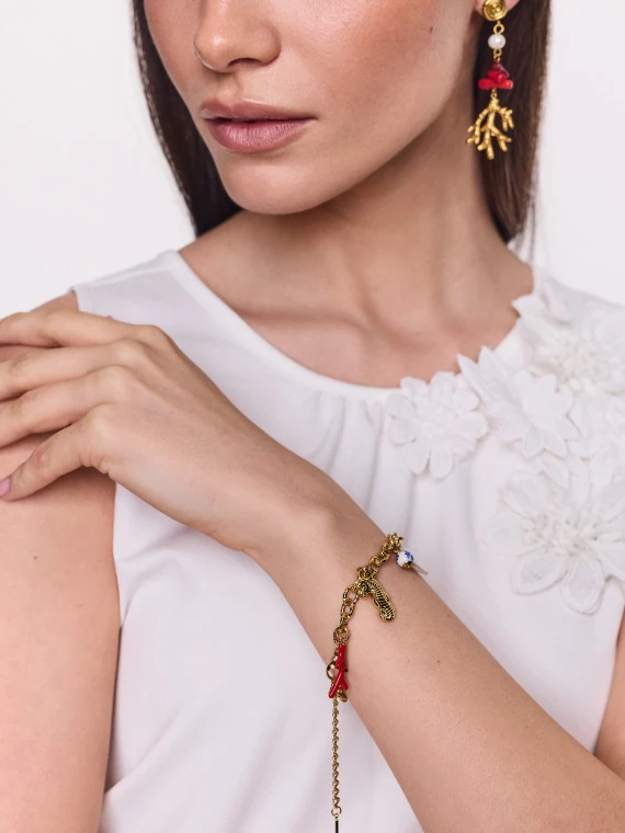 A gold-colored bracelet with seashell charms featuring a natural pearl