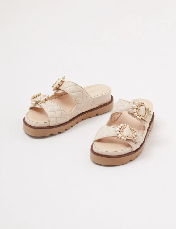 Cream-colored leather flip-flops with decorative buckles