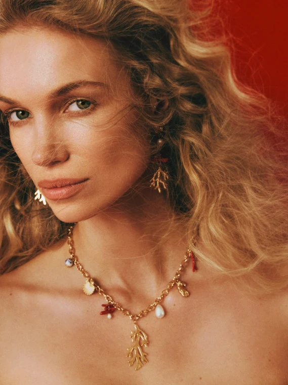 A gold-colored necklace with decorative pendants featuring a natural pearl