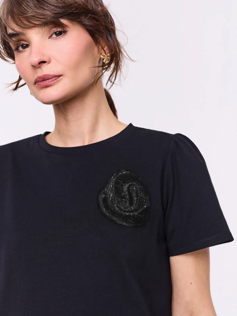 Black short-sleeved blouse with a flower-shaped brooch