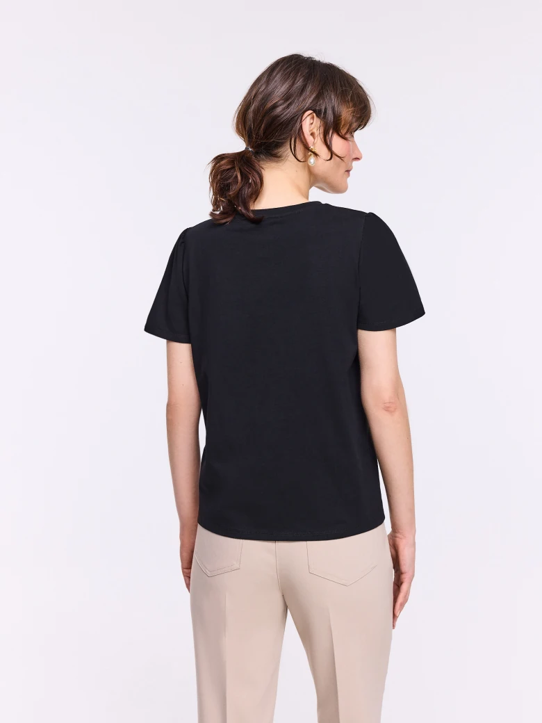 Black short-sleeved blouse with a flower-shaped brooch