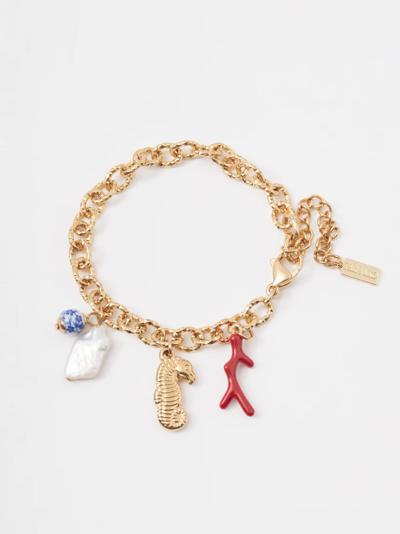 A gold-colored bracelet with seashell charms featuring a natural pearl