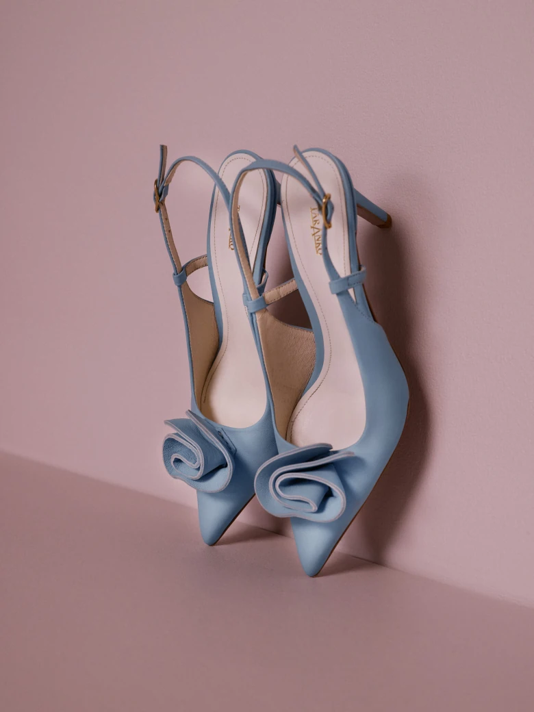 Light blue leather pumps with a flower detail and an open heel