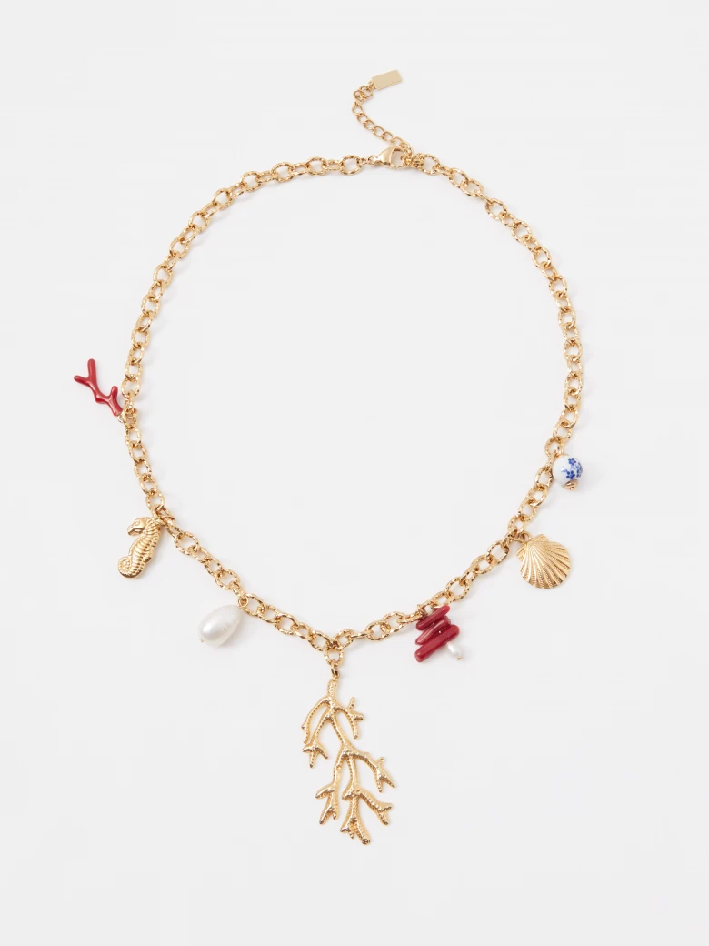 A gold-colored necklace with decorative pendants featuring a natural pearl